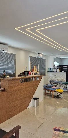 Recepção da Quiro Life, com balcão de madeira e macas ao fundo